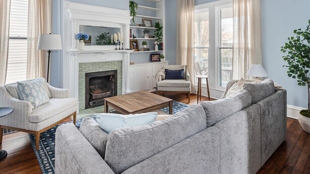Een woonkamer met een open haard, een bank, een fauteuil en een salontafel.