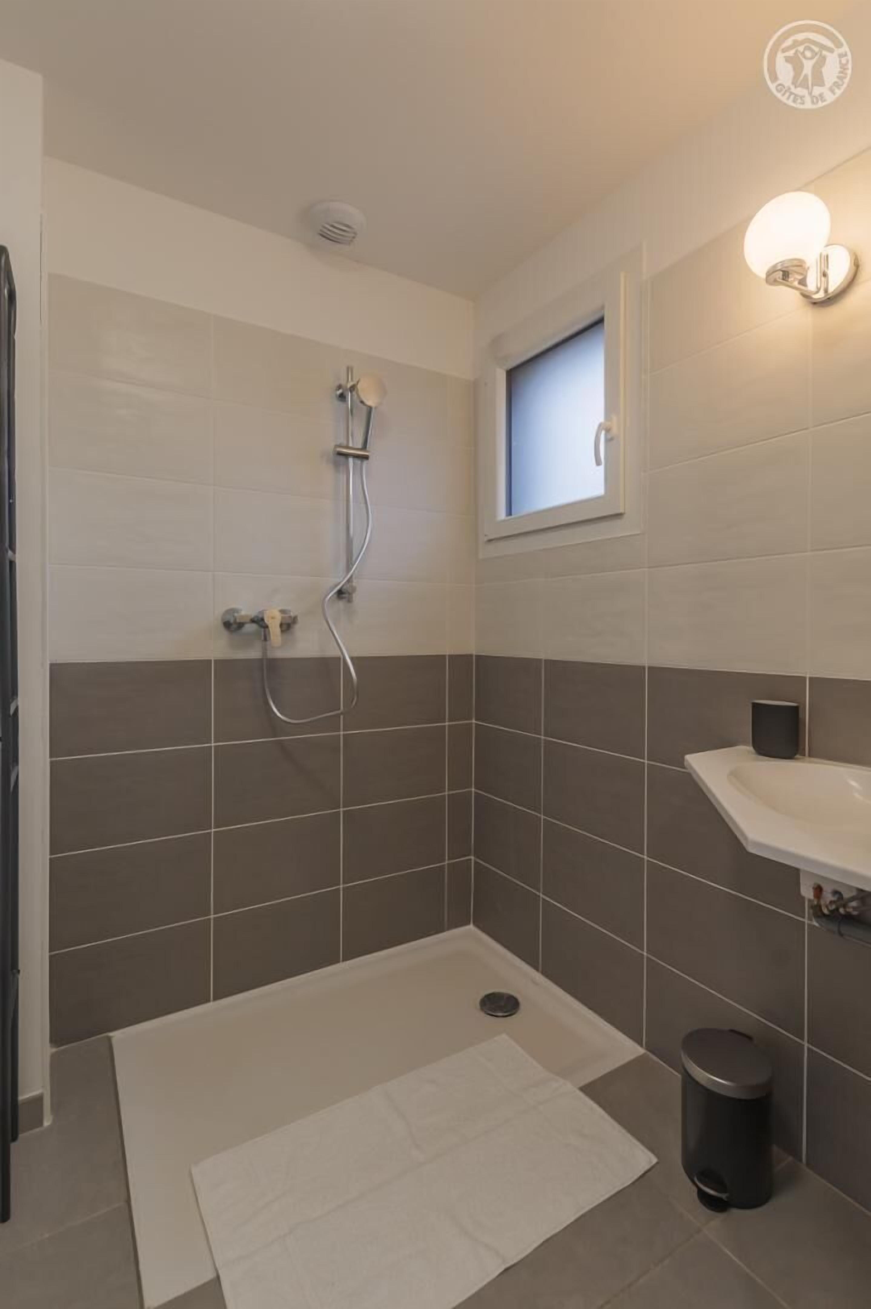 Un baño moderno con ducha, lavabo y ventana.