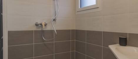 Un baño moderno con ducha, lavabo y ventana.