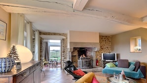 Una sala de estar acogedora con una chimenea de piedra, televisión y un espacio de descanso cómodo.