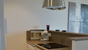 Una cocina compacta con lavadora, cafetera y lavabo.