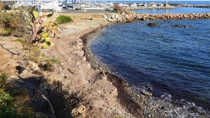Una marina costera con barcos, un litoral rocoso y un edificio con balcón.
