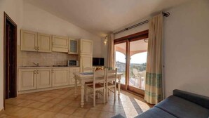 A compact living space with a kitchenette, a dining area, and a balcony with a view. - Holiday apartment mit Klimaanlage und Meerblick (Badesi)