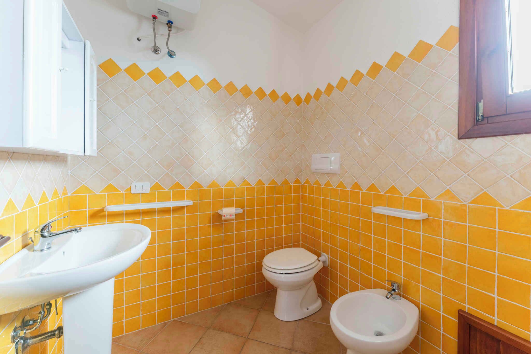 A bathroom with yellow and white tiles, a toilet, a bidet, and a sink.