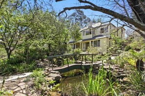 A house with a pond, surrounded by trees and a bridge. - Beautiful Architecturally Designed Cottage in Blue Mountains w/ Valley Views (Hazelbrook)