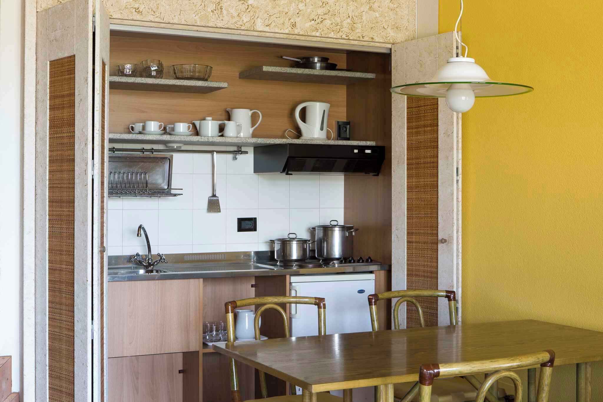 A compact kitchen with a dining area, featuring a built-in oven, a sink, and a stove.