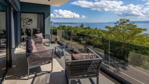 A balcony with outdoor seating, a view of the sea, and a modern building facade. - Beautiful home in Kostrena (Kostrena)