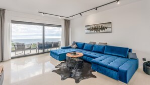 A modern living room with a blue sectional sofa, a round coffee table, and a cityscape artwork on the wall. - Beautiful home in Kostrena (Kostrena)