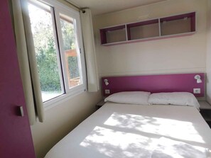A bedroom with a bed, a window, and a wall-mounted shelf.