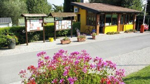 A small yellow building with a tiled roof, a bicycle parked outside, and a signboard with information.