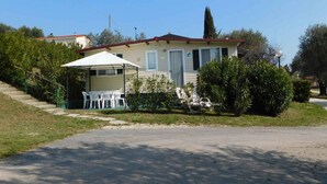 A single-story house with a covered patio area, a staircase leading up to the entrance, and a well-maintained lawn.