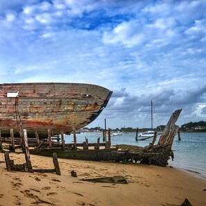 A large, rusted boat on a sandy beach with a calm sea in the background. - Le Sémaphore : Gite Le Nohic (PLOUHINEC)