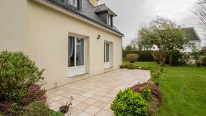 A house with a tiled patio, a small garden, and a neighboring property.