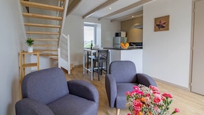 A modern apartment with a wooden staircase, a dining area, and a kitchen.