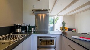 A modern kitchen with stainless steel appliances, a built-in oven, and a large window providing natural light.