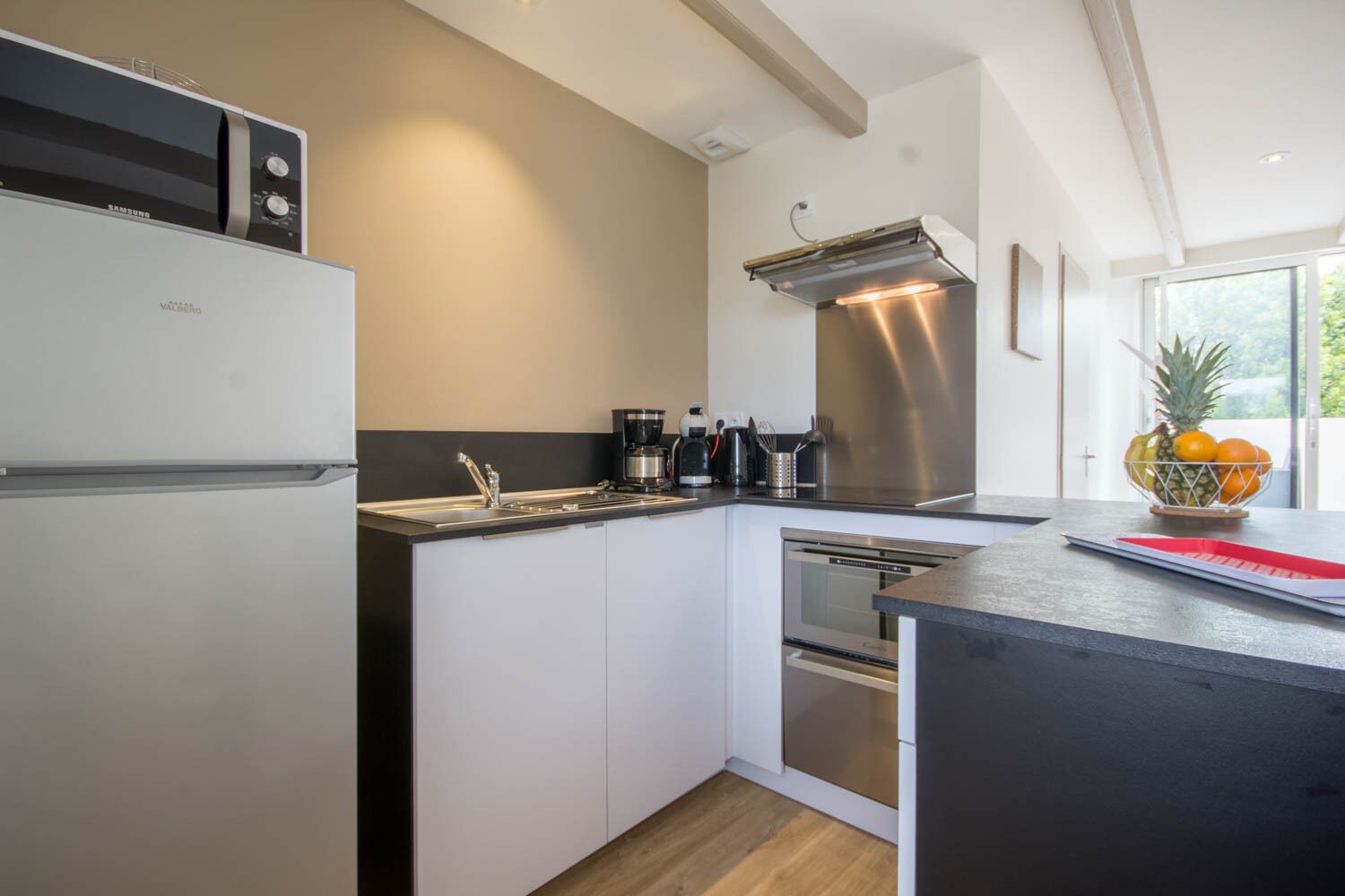 A modern kitchen with a built-in dishwasher, a stainless steel range hood, and a fruit bowl on the counter.