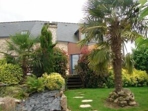 Stroll through the serene garden, surrounded by lush palm trees and vibrant shrubs, leading to the entrance of the building.