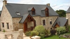 Un bâtiment en pierre doté d’un toit en pente, de nombreuses fenêtres et d’un petit porche.