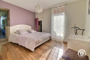A bedroom with a bed, a chair, a desk, and a window with curtains. - Le Gîte du Procureur (MONTERBLANC)