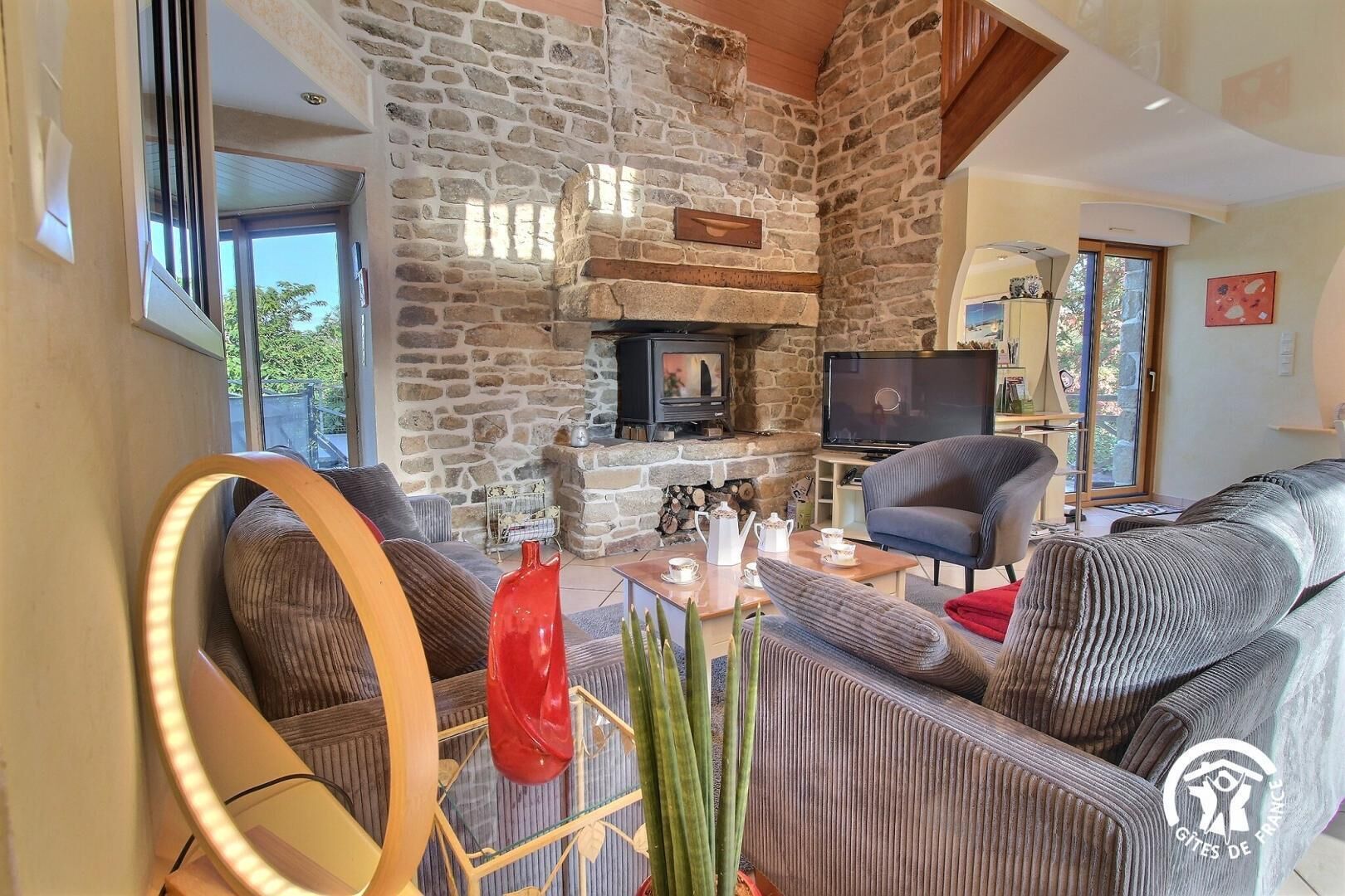 A living room with a stone fireplace, a television, and modern furniture.