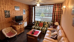 Una sala de estar acogedora con un sofá, una silla, una mesita de centro y un televisor.