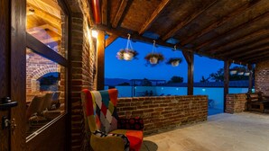 A cozy outdoor seating area with a brick wall, a wooden ceiling, and hanging flower baskets.