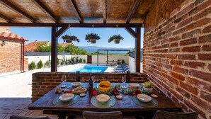 A dining area with a table set for a meal, a pool, and a view of mountains.