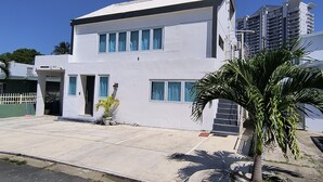Un edificio blanco de dos pisos con techo plano, ventanas grandes y un pequeño porche.