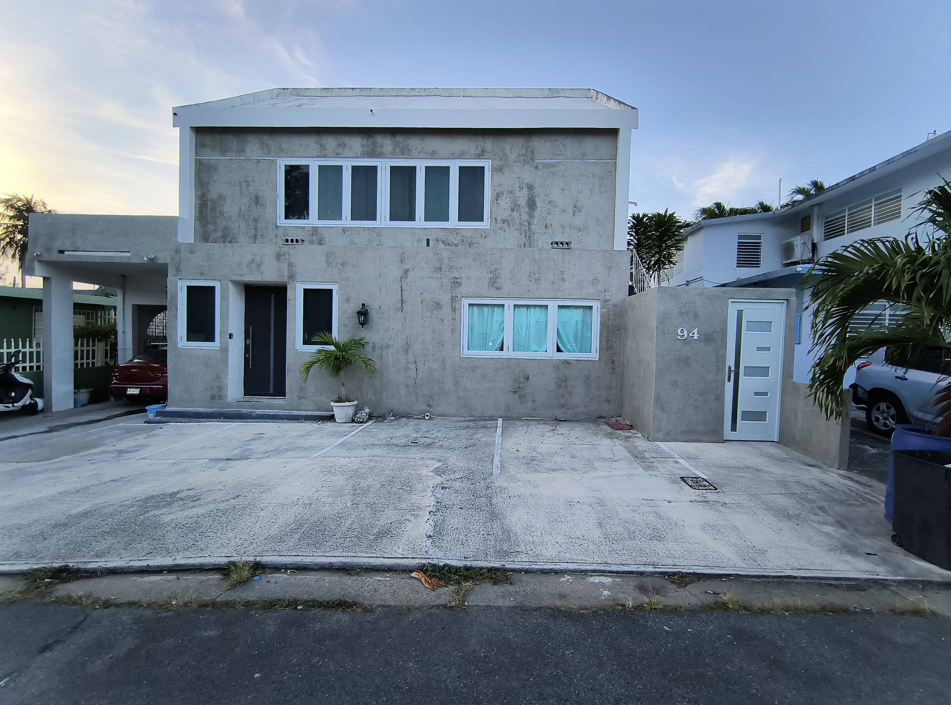 A two-story building with a garage, a potted plant, and a number 94 on the door.