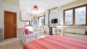 Une chambre à coucher avec un lit, un bureau, une télévision et une fenêtre donnant sur des arbres.
