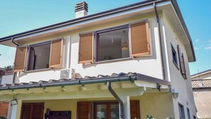 Un bâtiment à deux étages, doté d’un toit plat, de nombreuses fenêtres avec volets et d’un appareil de climatisation visible.