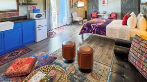 Une chambre confortable comprenant un lit, un canapé, un coin repas avec une table et des chaises, ainsi qu’un coin cuisine avec un réfrigérateur et un four à micro-ondes.