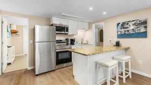 A modern kitchen with stainless steel appliances, a granite countertop, and white cabinetry.