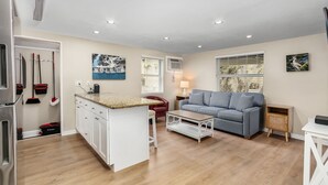 A modern living room with a kitchen area, a sofa, a coffee table, and a dining table.