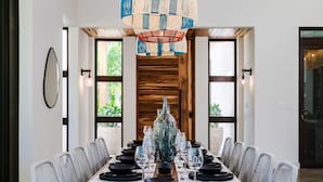 Mesa de comedor con cubierta de madera dispuesta para seis comensales, rodeada de sillas tapizadas en gris.