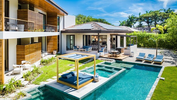 Una casa moderna de dos plantas con piscina, mobiliario exterior y un patio cubierto.