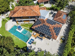 A residential property with a swimming pool, solar panels, and a tiled roof.