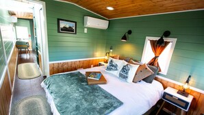 Una habitación acogedora con cama, mesita de noche con lámpara, una silla y ventana con cortinas.