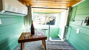 Una habitación pequeña y acogedora con una mesa de madera, una ventana con vistas a la vegetación y una pared verde.