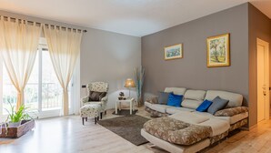 A living room with a sofa, armchair, and a small table with a lamp. There are two framed pictures on the wall. - Graziella by Interhome (Leggiuno)