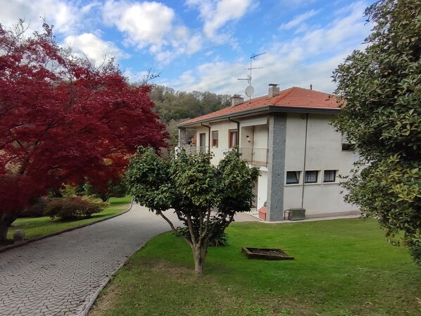 Ein zweigeschossiges Haus mit rotem Ziegeldach, befestigter Auffahrt und gepflegtem Rasen.