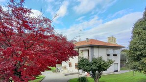A two-story building with a tiled roof, a paved driveway, and a well-maintained lawn. - Graziella by Interhome (Leggiuno)