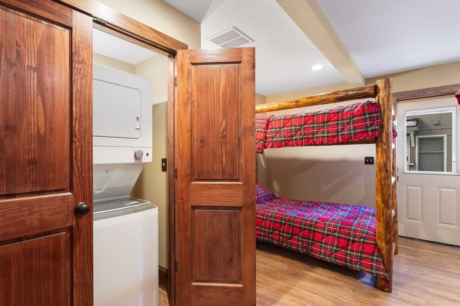 A room with a bunk bed, a washing machine, and a wooden door.