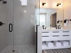 A modern bathroom with a glass-enclosed shower, a white vanity with two sinks, and a mirror above the vanity.