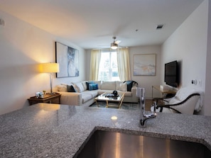 A modern hotel room with a kitchen area, a sofa set, a flat-screen TV, and a ceiling fan. - Home Suite ‘Sip at 514 by Apex Short Term Stays (Oxford)