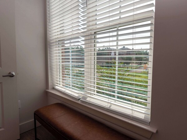 A room with a bench, a window with blinds, and a view of greenery outside. - Home Suite ‘Sip at 514 by Apex Short Term Stays (Oxford)