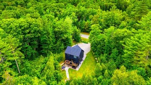 A house surrounded by dense forest with a clear view of mountains in the background. - NEW Chalet 6 minutes from Sunday River! Hot tub, Sauna, Sleeps 12, Dog Friendly! (Bethel)