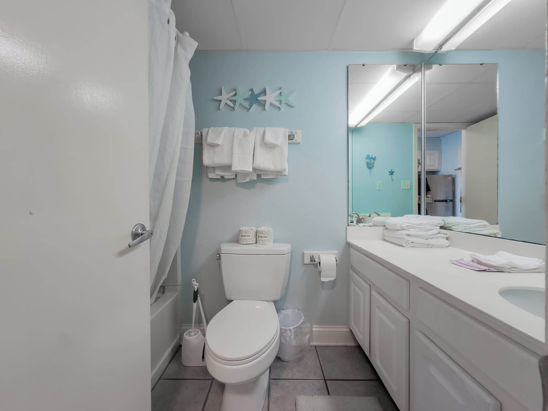 A bathroom with a toilet, a sink, a mirror, and a towel rack.