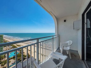 Een balkon met uitzicht op het strand en een zwembad.