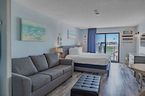 Ein Hotelzimmer mit Bett, Sofa, kleinem Tisch und einem Balkon mit Blick.